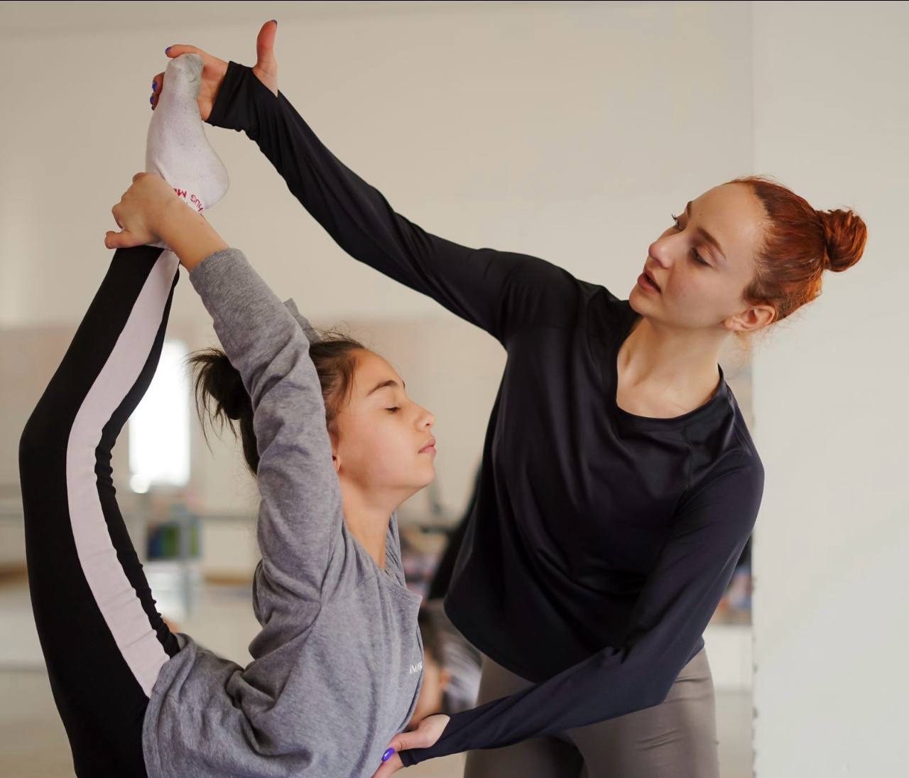 A coach guiding a child through a balance exercise